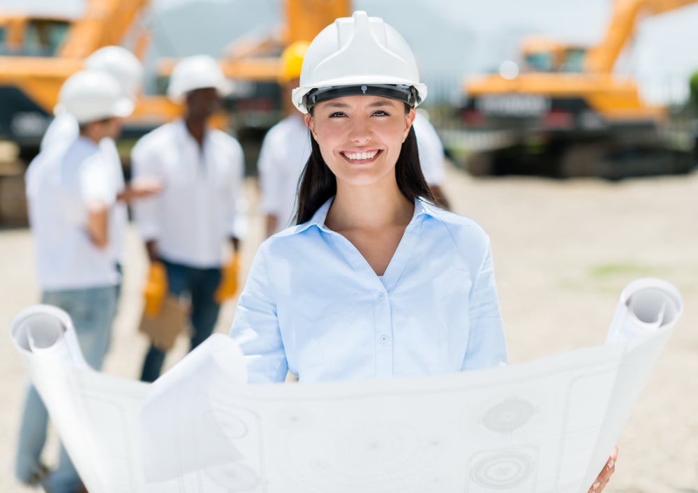 Female architect at a construction site holding blueprints