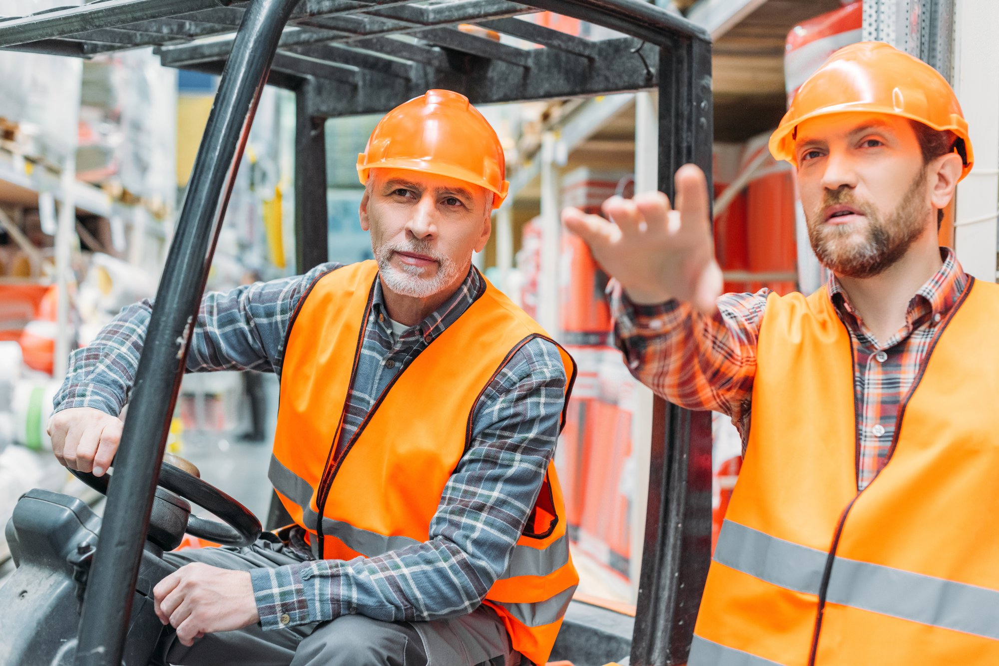 Experienced operator providing employer-paid forklift training to a warehouse worker Experienced operator providing employer-paid forklift training to a warehouse worker